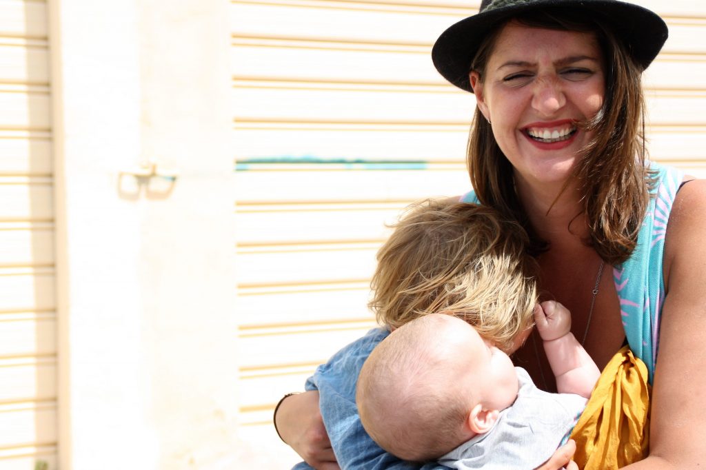 Woman in blue shirt carrying baby in orange shirt